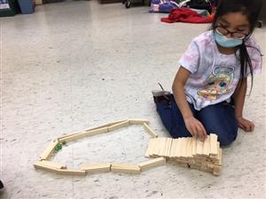 Student demonstrating how her wooden block marble run works